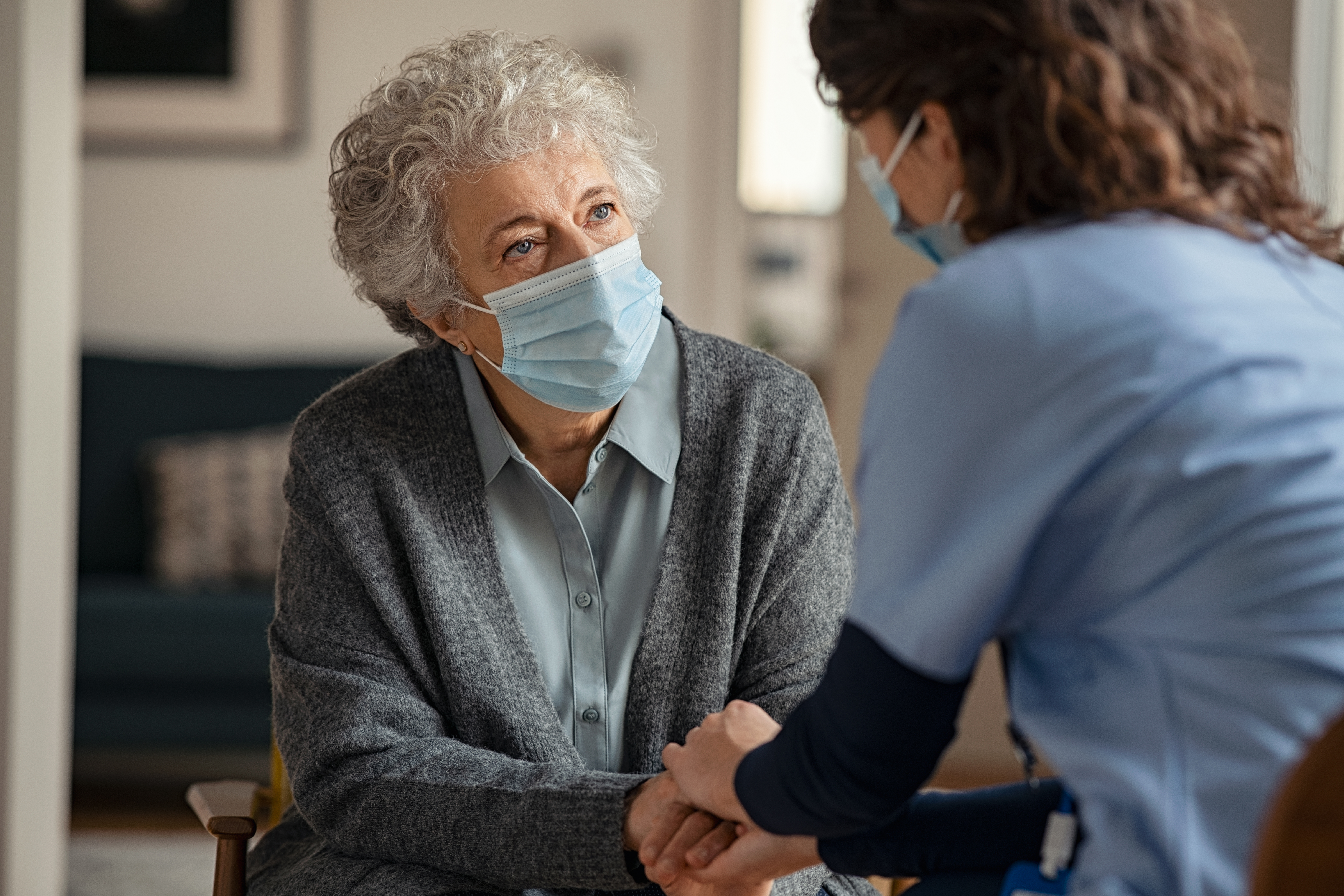 Female doctor consoling senior woman wearing face mask during home visit 1284869020 6192x4128 1